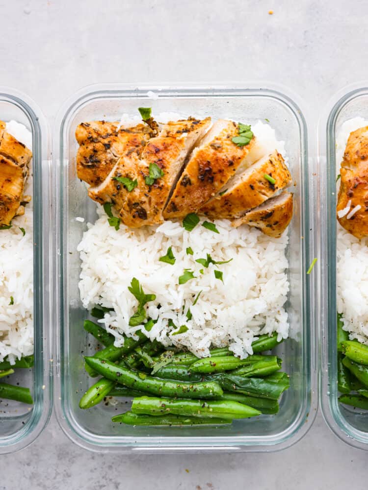 Top-down view of a plastic container filled with grilled chicken, white rice, and green beans.