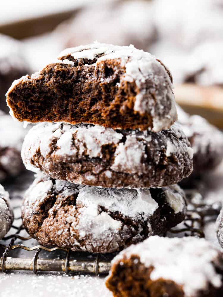 Close up side view of chocolate crinkle cookies stacked on top of each other with a bite missing from the top cookie