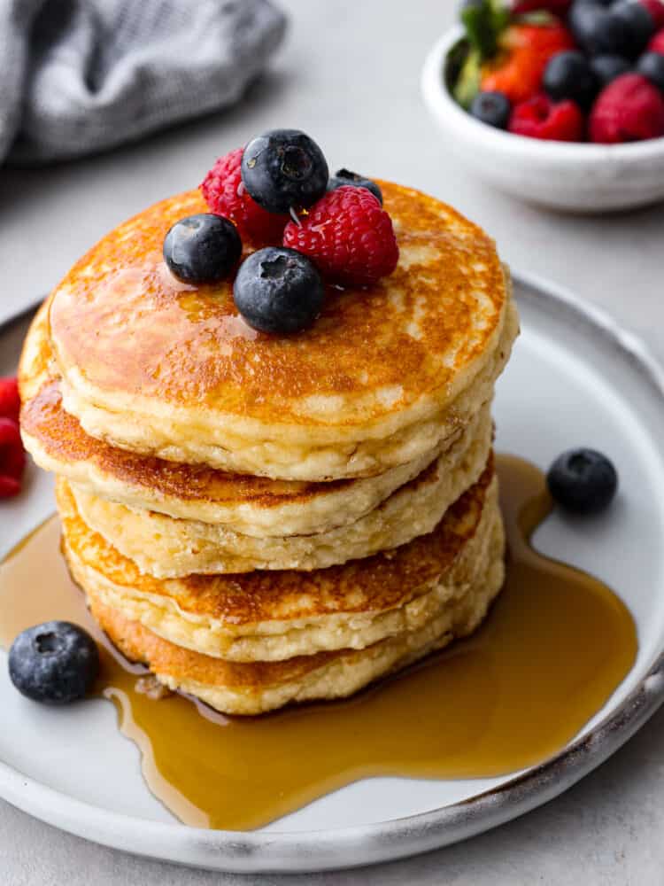 A stack of keto pancakes topped with syrup and berries.