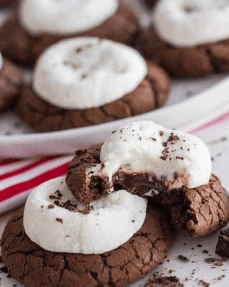 A stack of hot cocoa cookies, the top one with a bite taken out of it. 