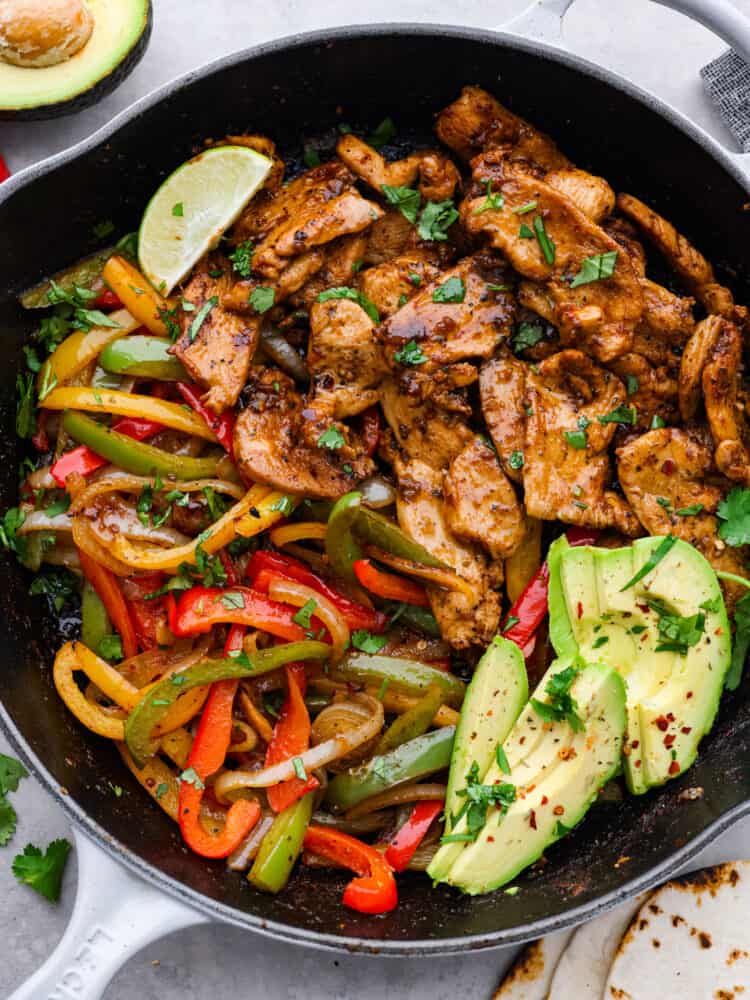 Chicken fajitas in a skillet with fresh lime and cilantro
