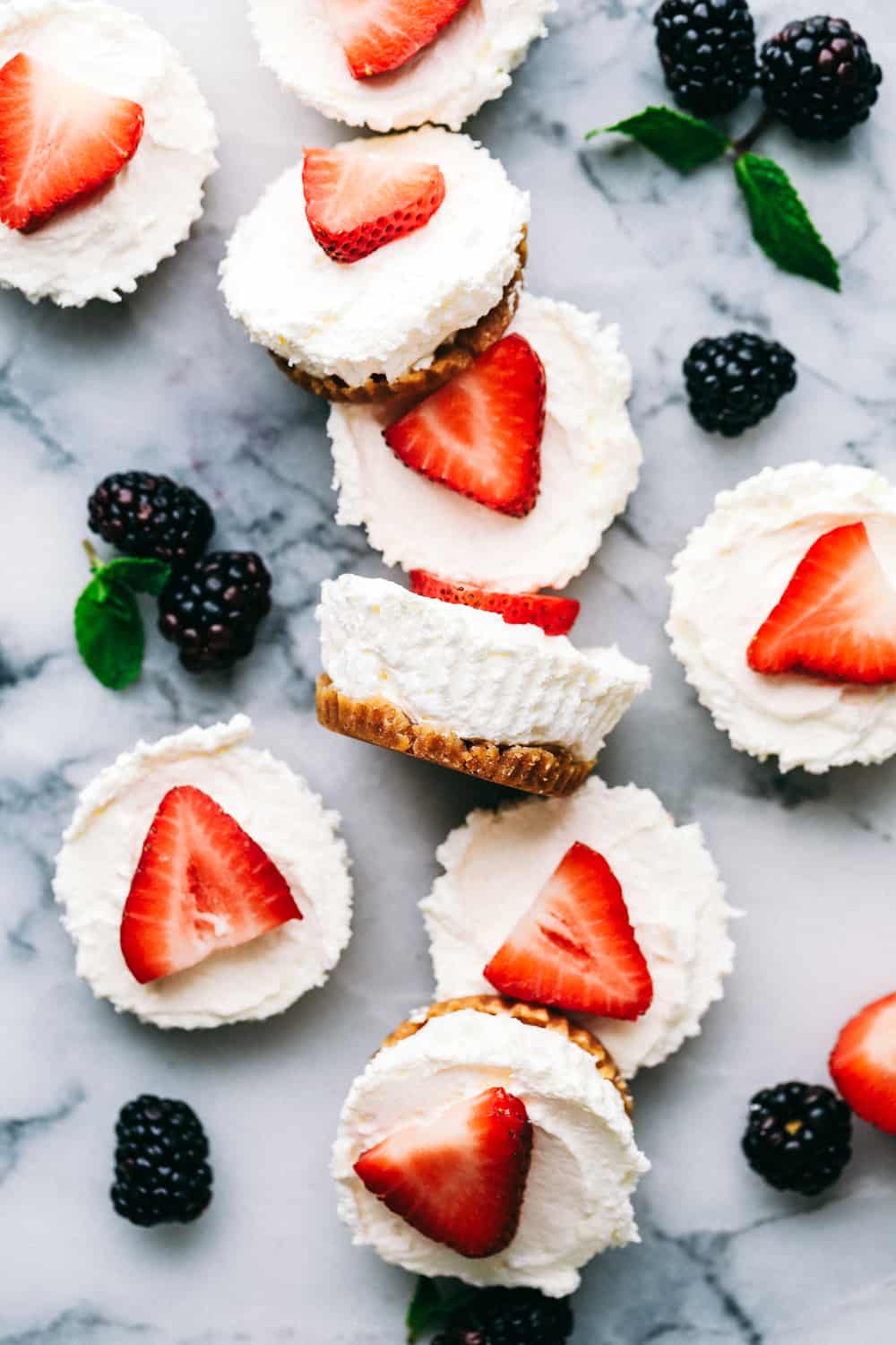 Skinny Mini Cheesecake bites on a marble counter with blackberries inbetween.