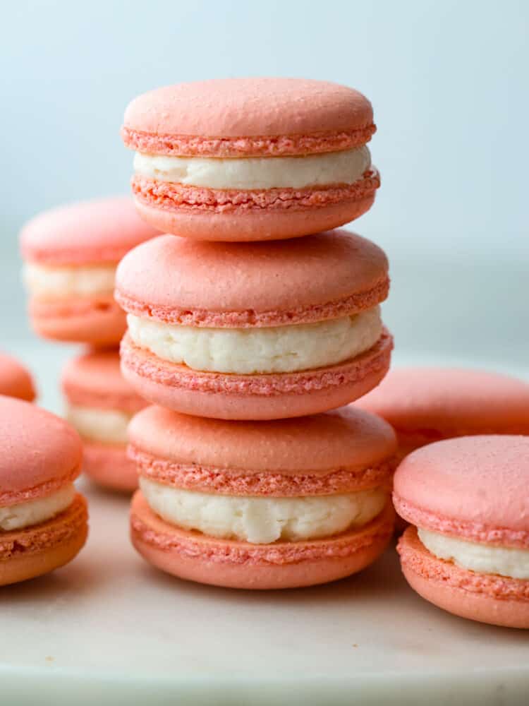 Three macarons stacked on top of each other with other macarons around it.