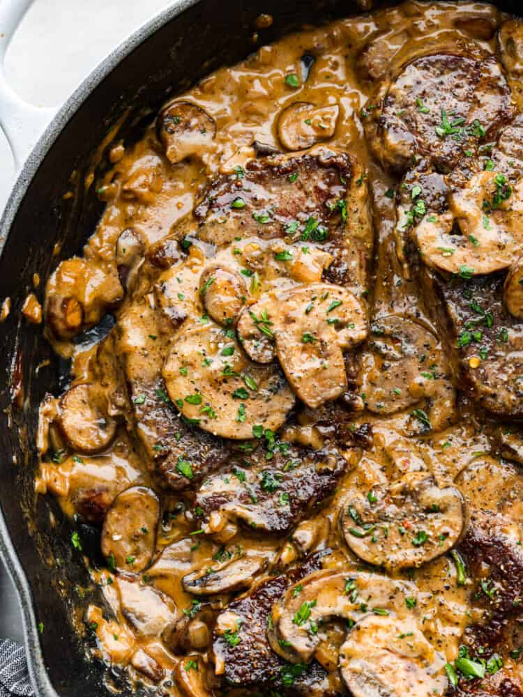 A close up of all the mushrooms and steak in a black skillet