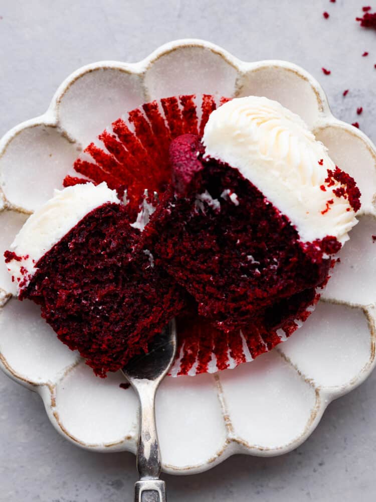 A cupcake cut in half and served on a white plate.
