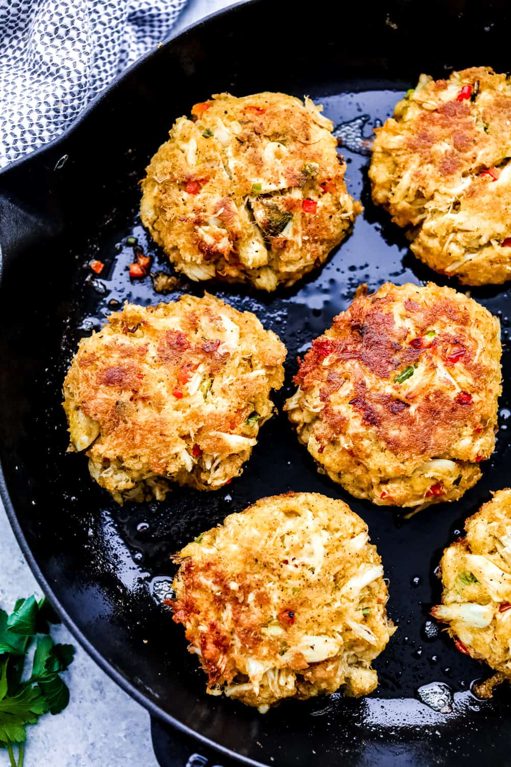 Crab cakes on a skillet cooking.