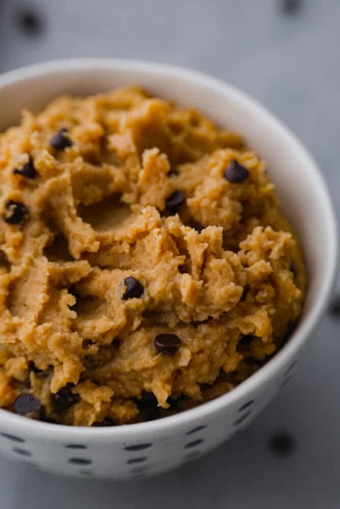 Closeup of chocolate chip cookie dough in a white bowl.