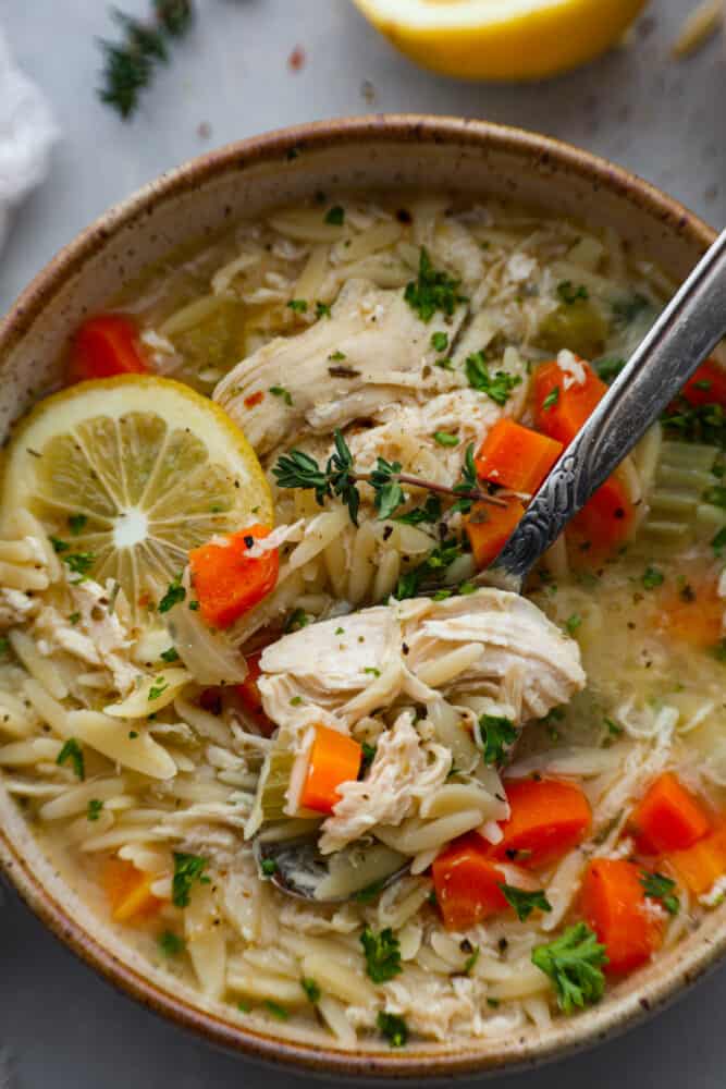 A close up on a bowl of lemon chicken orzo soup.