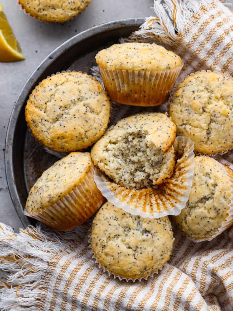 Top-down view of multiple lemon poppyseed muffins One has a bite taken out of it.