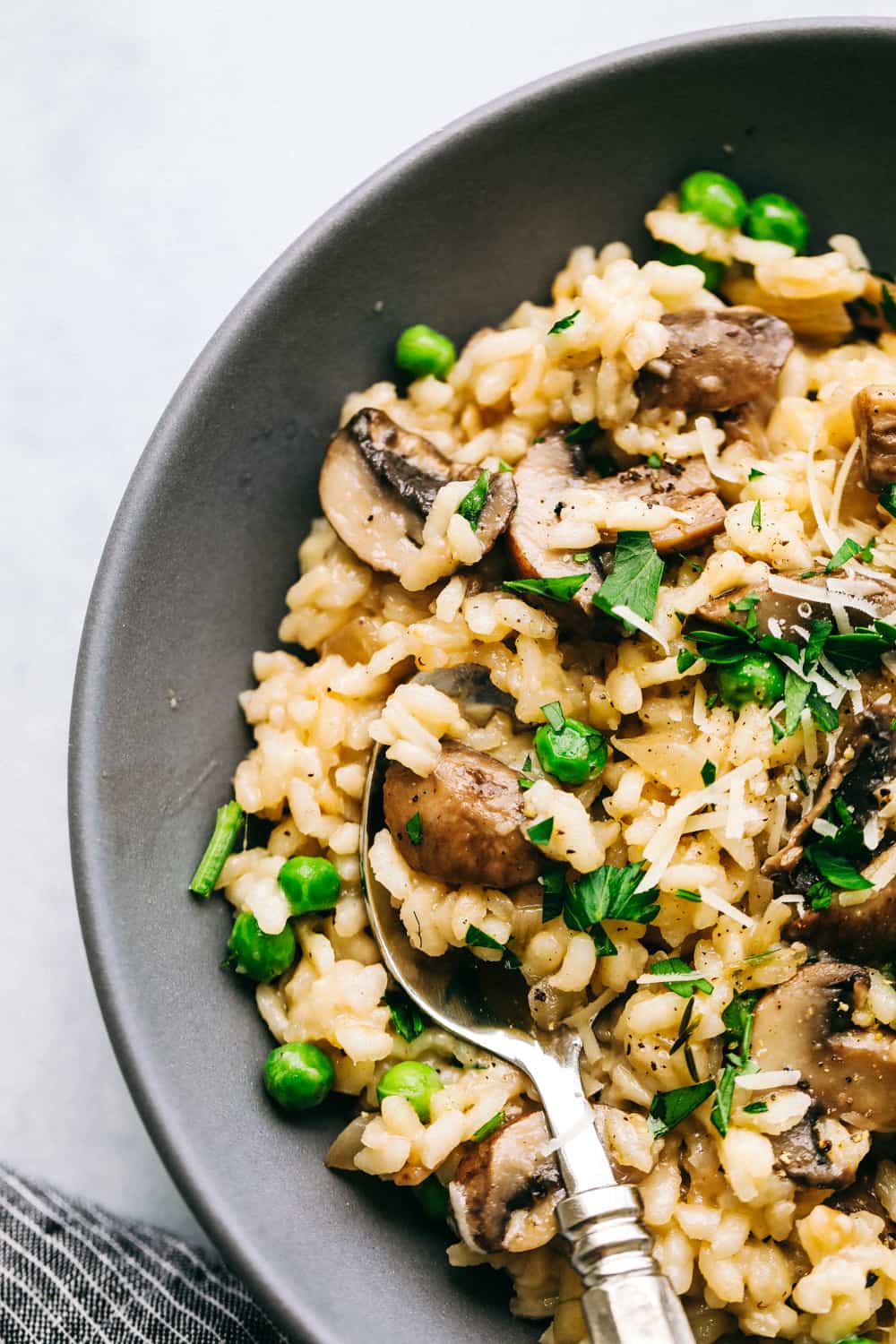 Creamy Mushroom Risotto in a black bowl with a spoon.