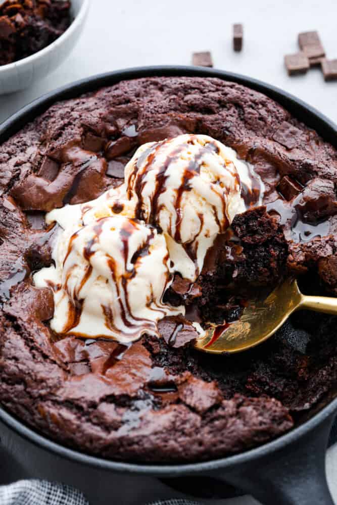 Hero image of a skillet brownie topped with ice cream and chocolate sauce.