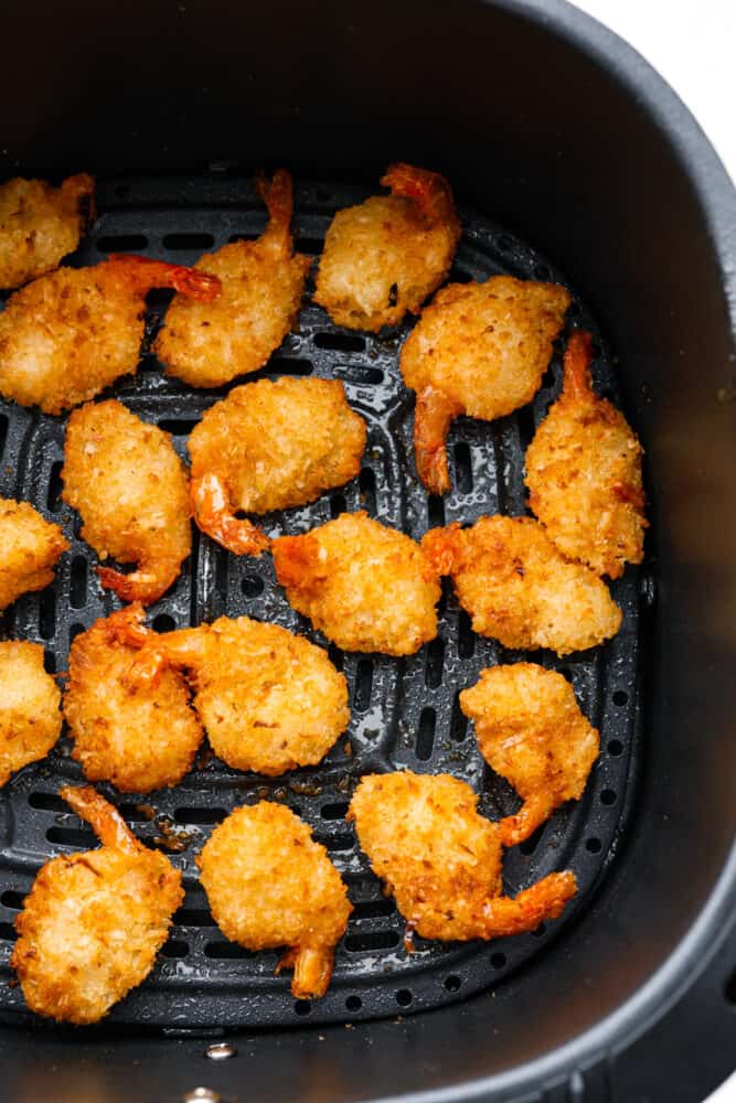 Cooked shrimp in the bottom of an air fryer basket.