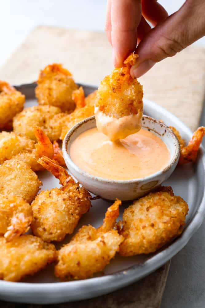 A piece of shrimp being dipped into a creamy sauce.