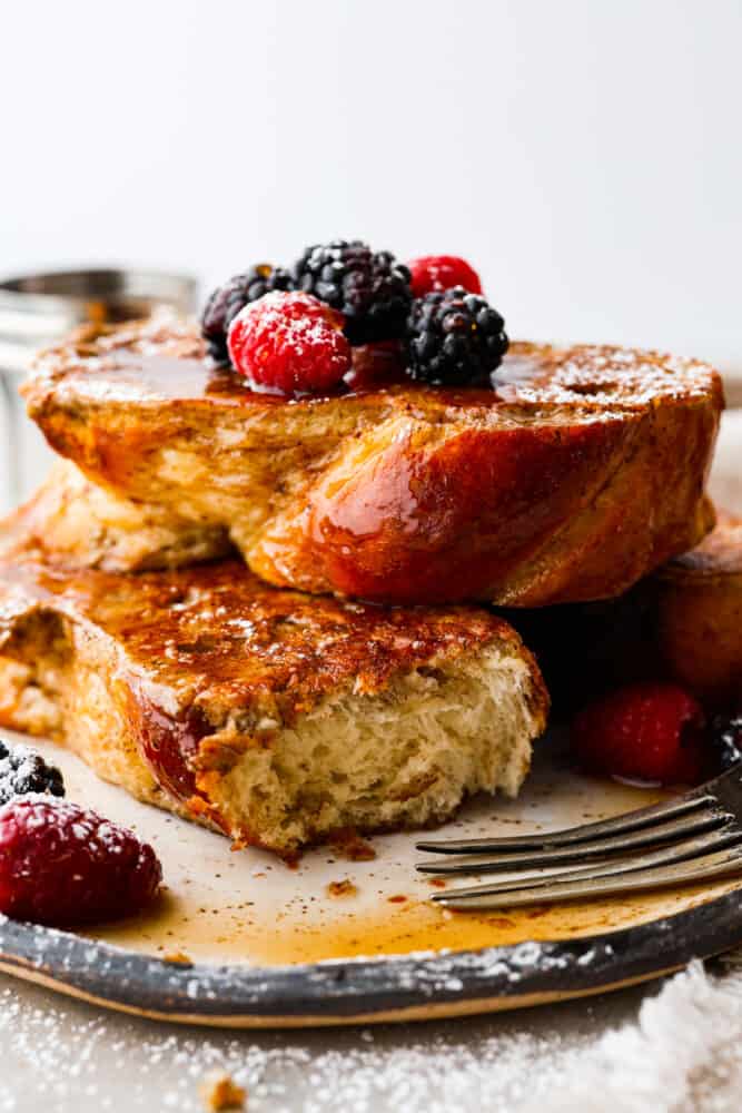 Two slices of brioche French toast, one has a bite taken out of it.