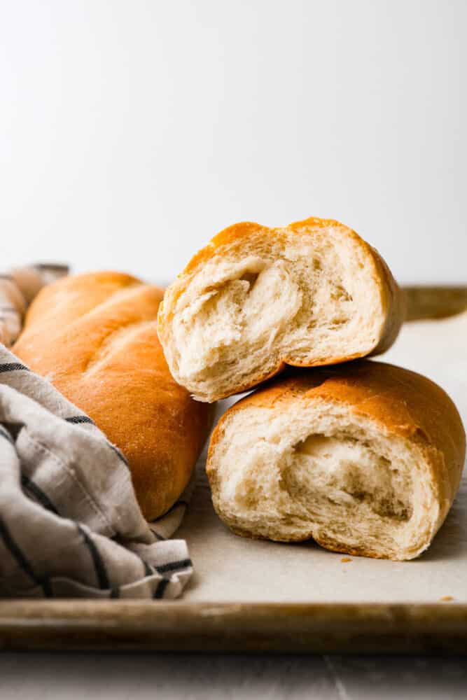 Italian bread ripped in half and stacked on top of each other showing the fluffy inside.