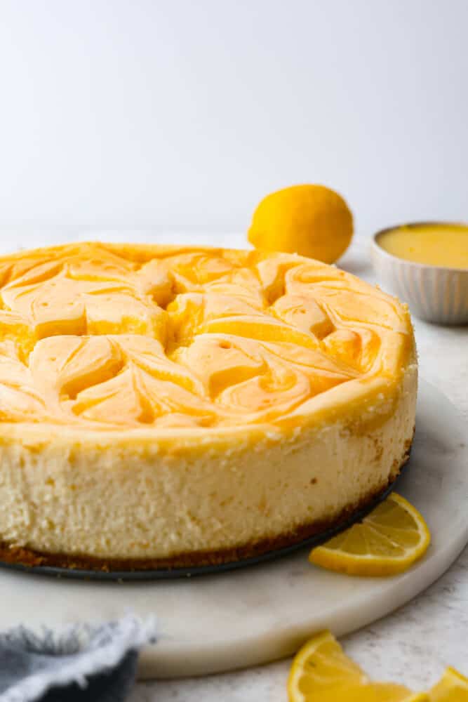 A whole cheesecake topped with swirls of lemon curd.