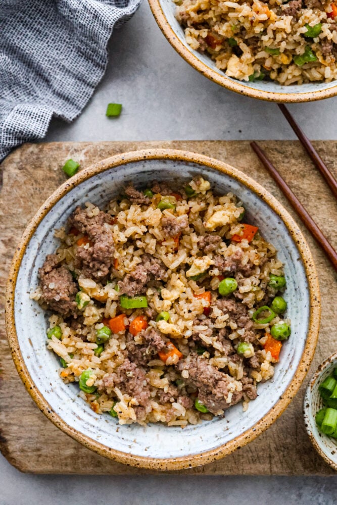 Beef fried rice in a bowl with chop sticks next to it.