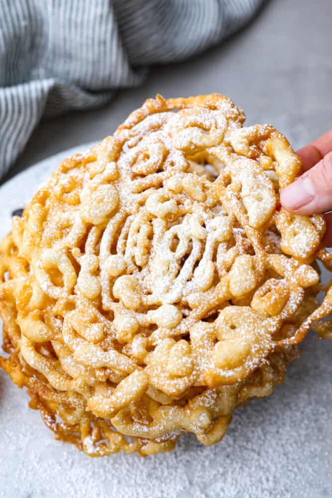A hand grabbing a funnel cake.