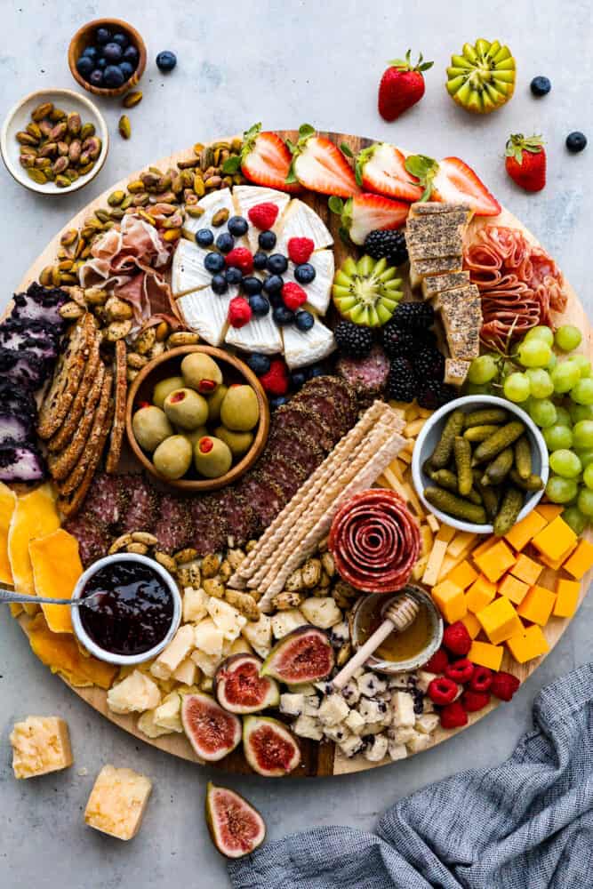 Hero image of a charcuterie board topped with various cheese, fruit, meats, nuts, and crackers.