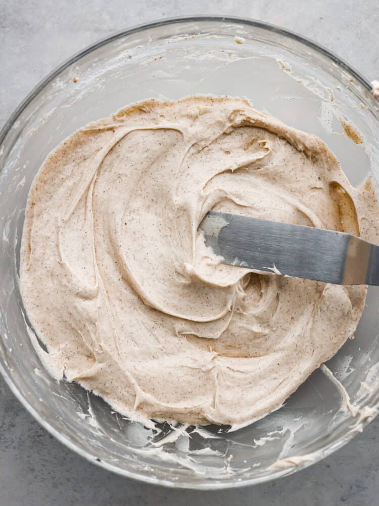 The top view of a glass bowl with cinnamon cream cheese frosting. 