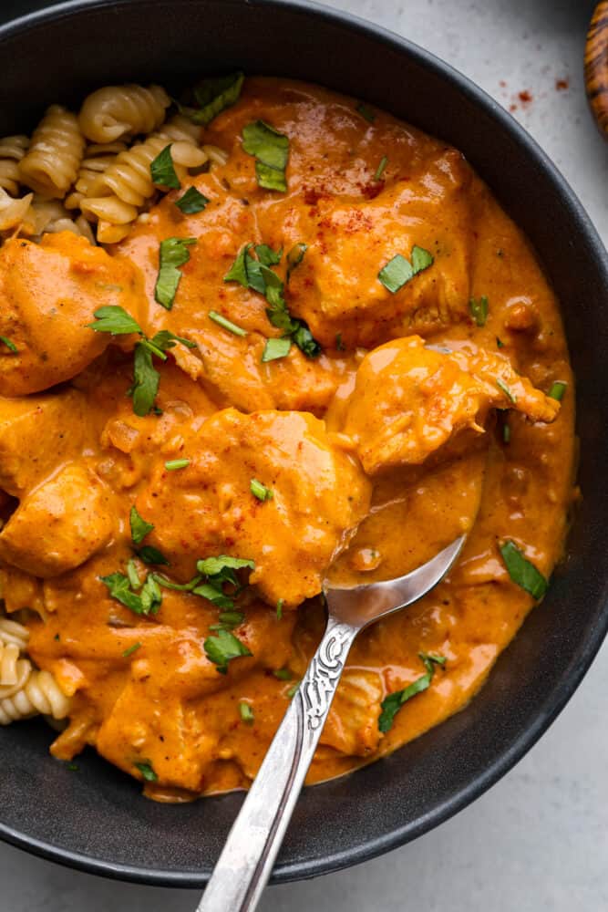 the top view of chicken paprikash in a bowl with a silver spoon. 