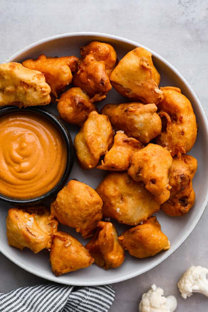 Top-down view of fried cauliflower bites served with dipping sauce.