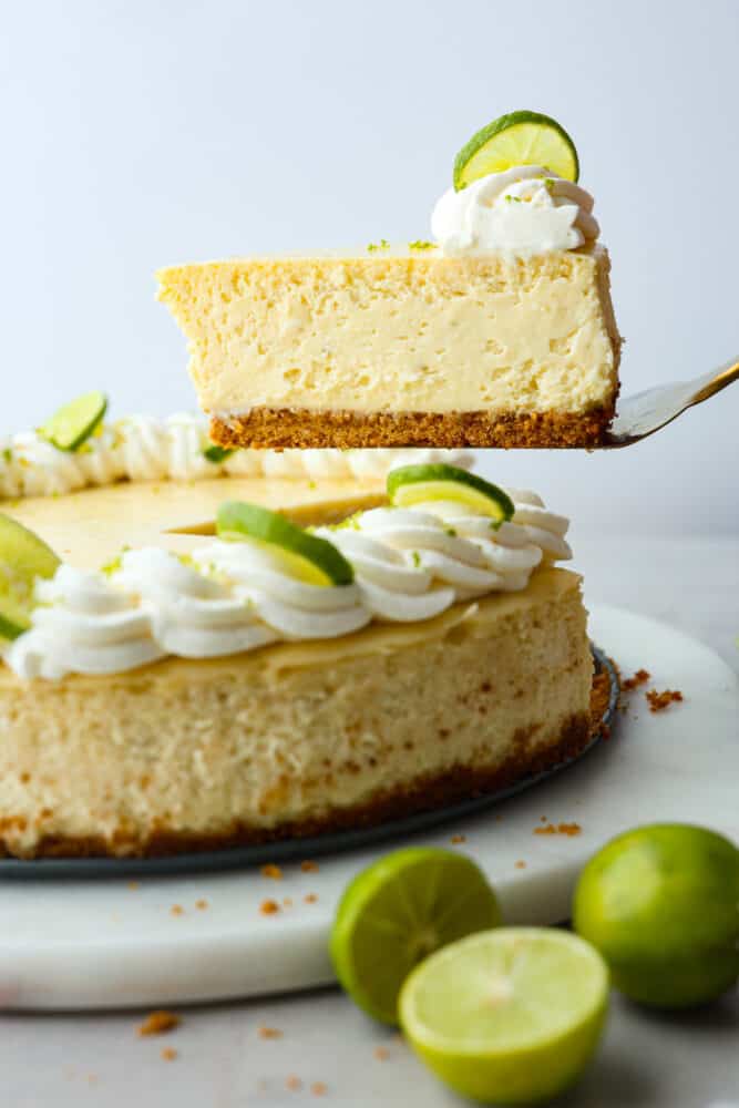 A slice of key lime cheesecake being served with a metal cake spatula.