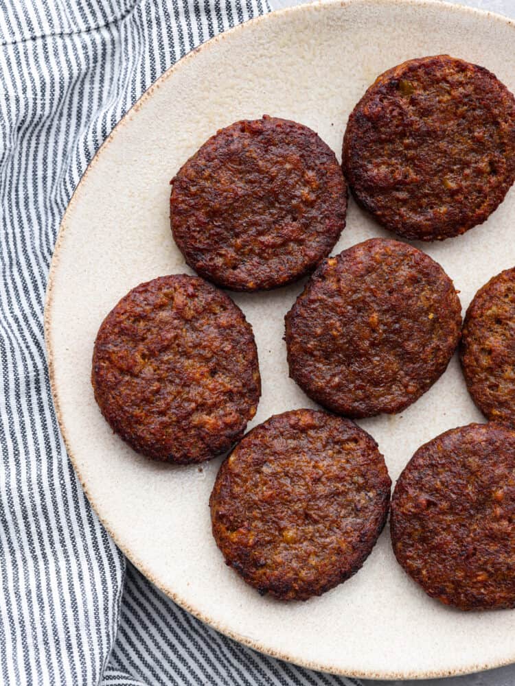 Cooked sausage patties on a white plate.