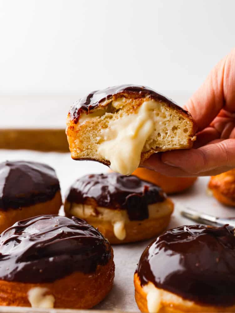 Someone holding a Boston cream donut that is cut in half. 
