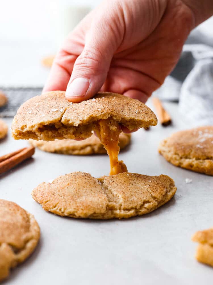 This recipe takes snickerdoodles to the next level! Made with brown butter and a salted caramel core, each bite is a sweet and nutty dream! Picking up half of a cookie.