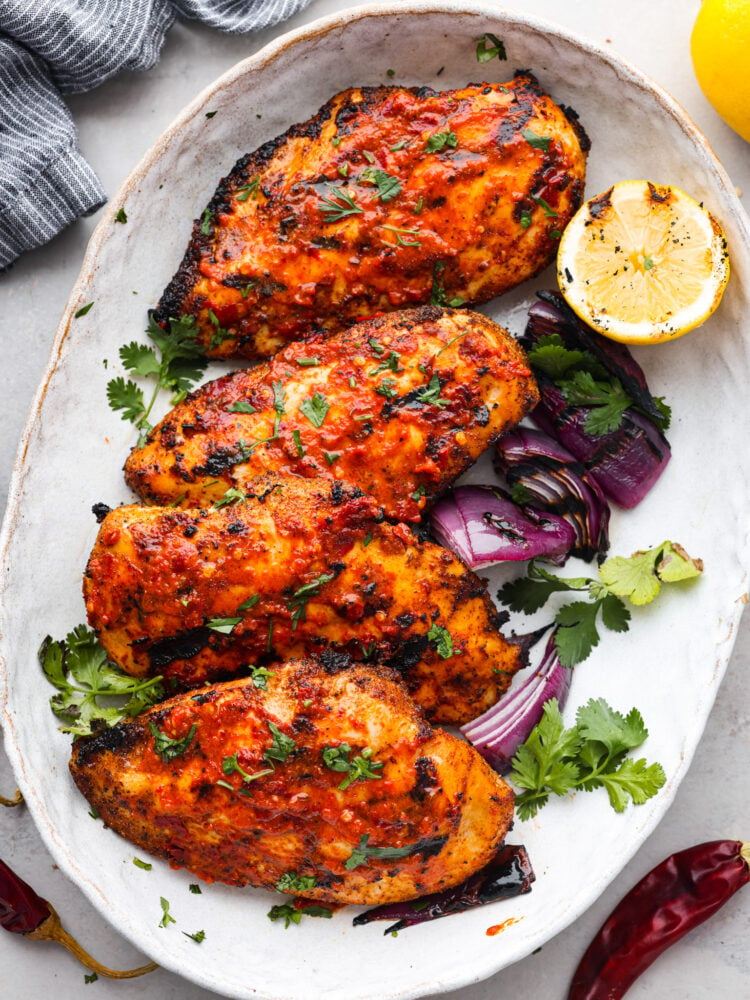 4 pieces of harissa chicken served with vegetables and half of a lemon.