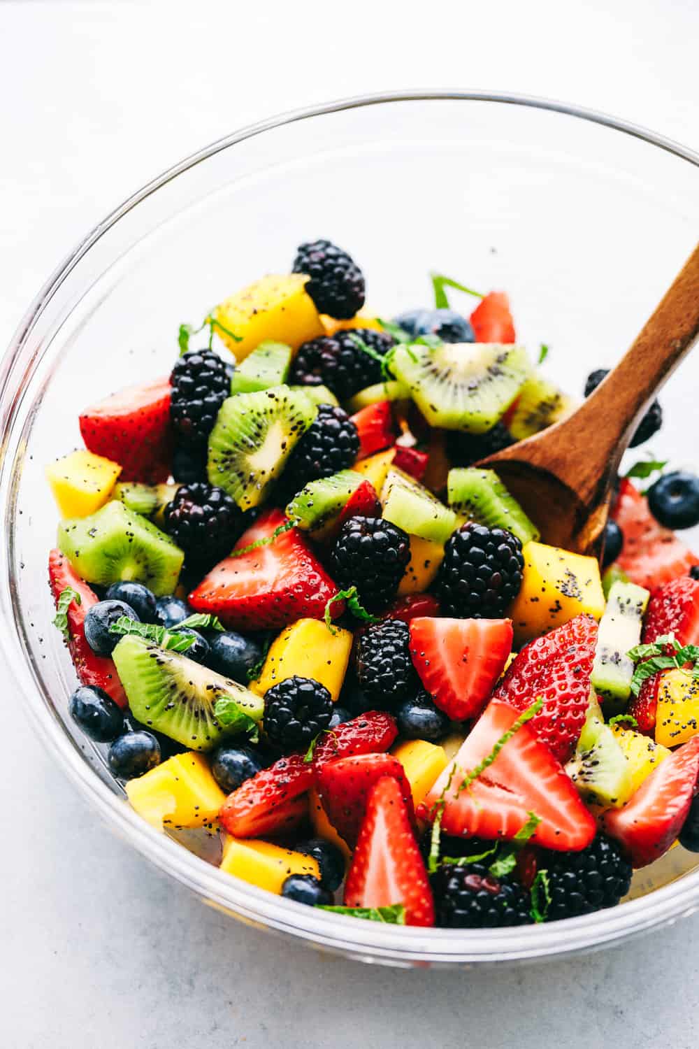 Honey lime poppy seed fruit salad in a glass bowl.