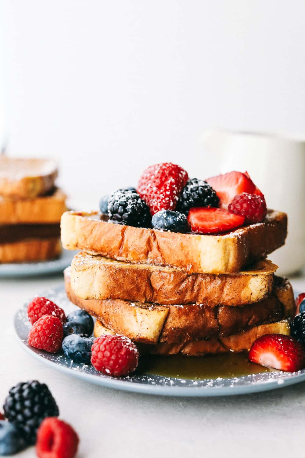 French toast stacked up with berries and powdered sugar on them. 