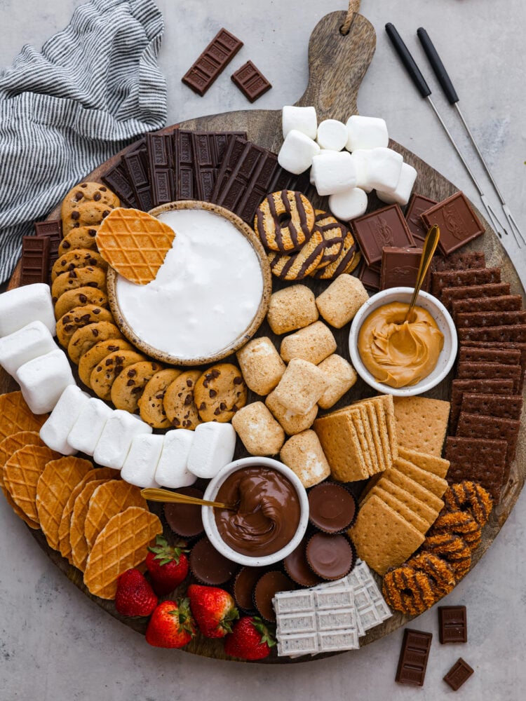 A whole s’mores charcuterie board made with various types of chocolate, marshmallows, and sweet spreads.