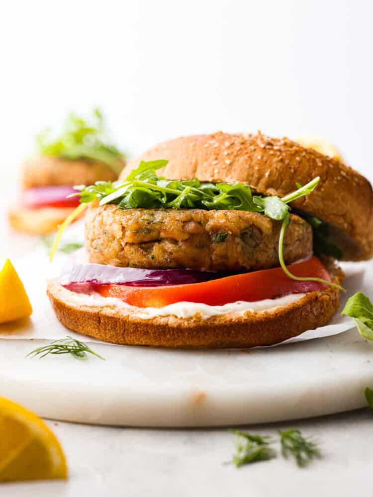 Hero image of a tuna burger topped with tomato and greens.