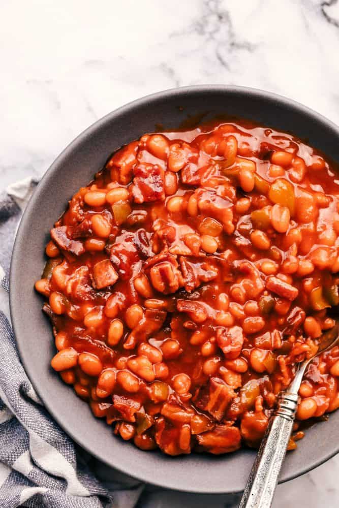 Baked Beans in a grey bowl with a metal spoon. 