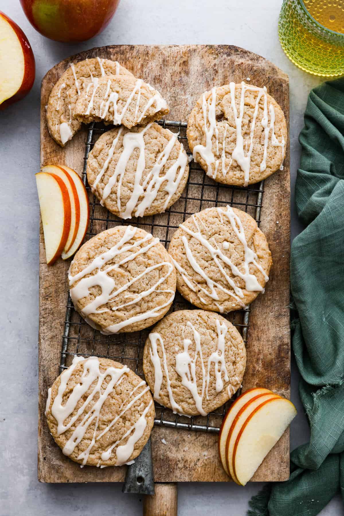 Apple cider cookies on a cutting board with apple slices surrounding them. 