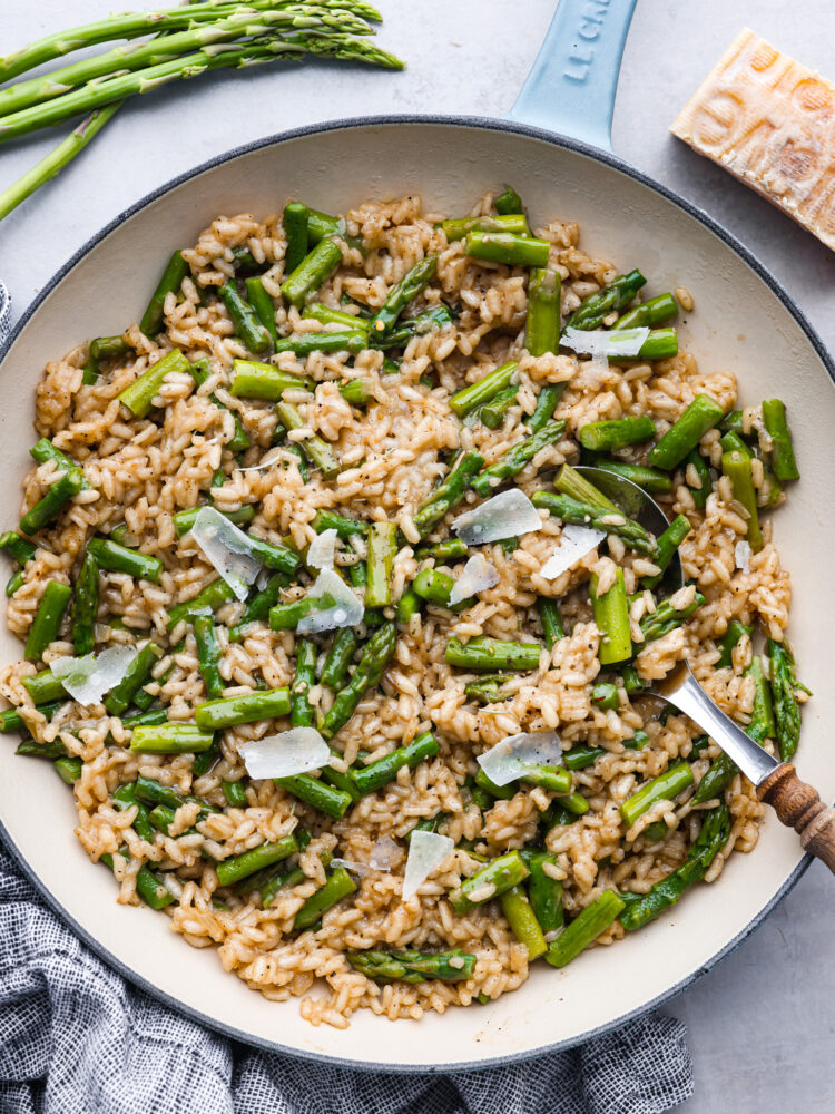 A bowl of arborio rice topped with asparagus and grated parmesan cheese.