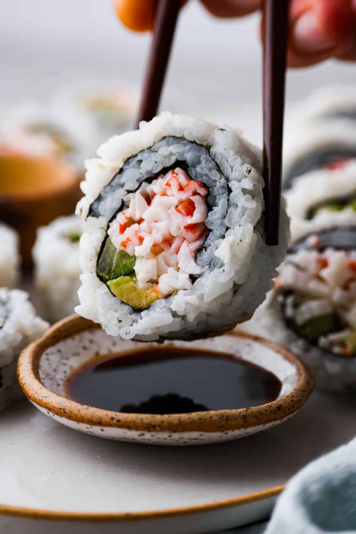 Closeup of a California roll being dipped in soy sauce.