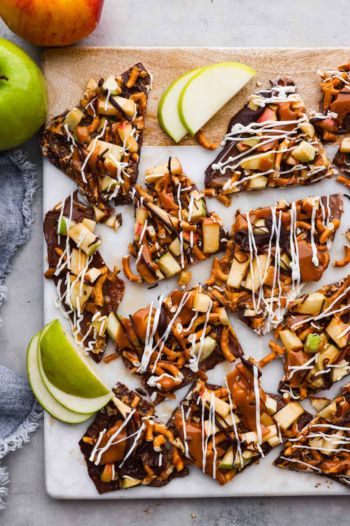 Top-down view of caramel apple bark on a wooden board, broken into pieces.