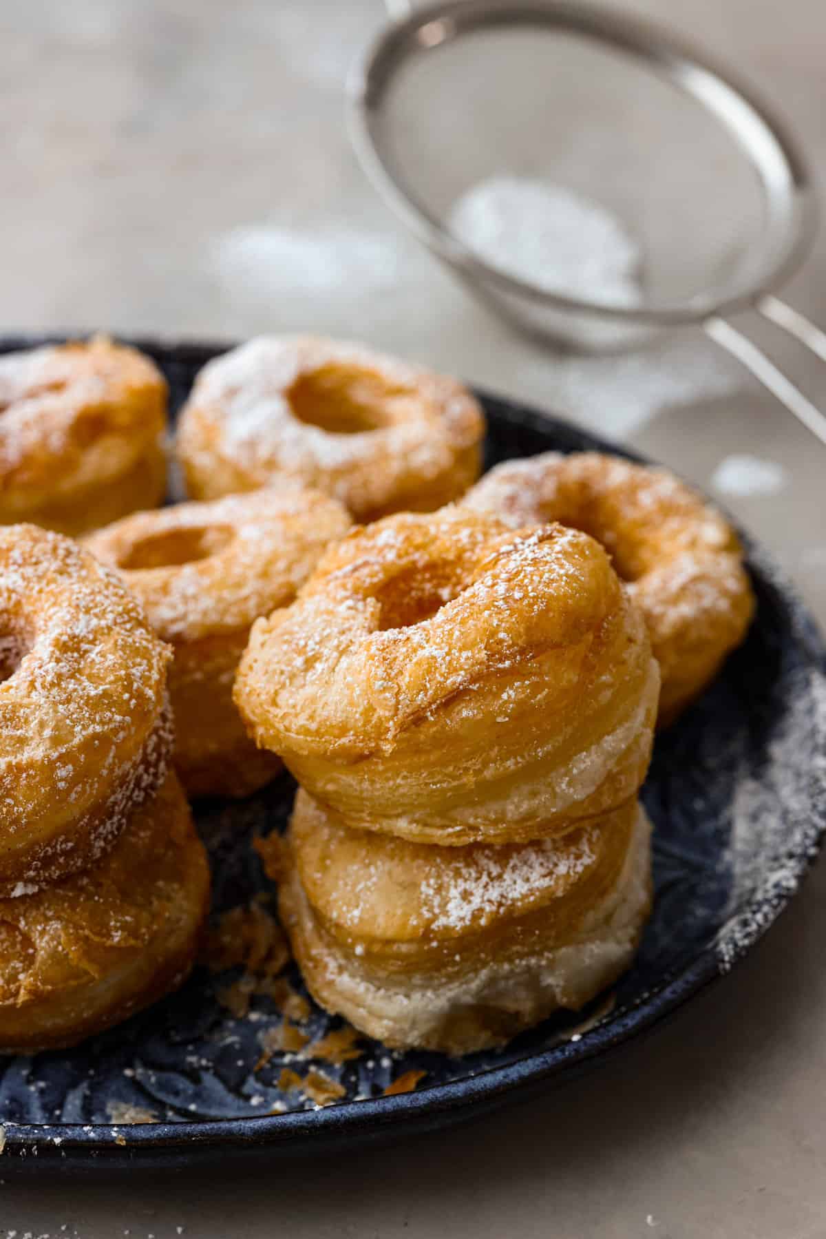 A platter of cronuts sprinkled with powdered sugar. 