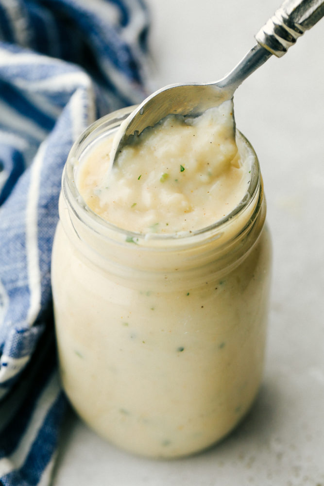 Close view of homemade cream of chicken soup in a glass jar with a spoon inside the jar.