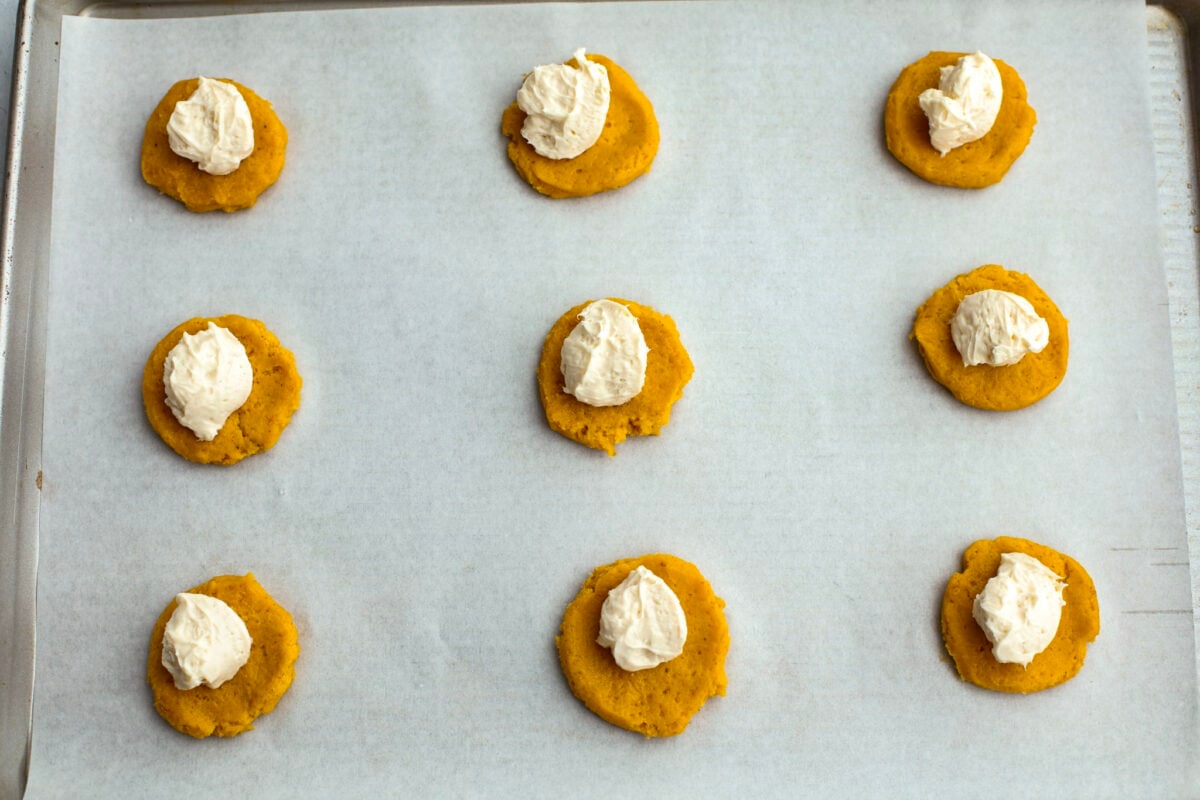 A process shot of pumpkin snickerdoodle dough flattened, each with a dollop of filling on top. 