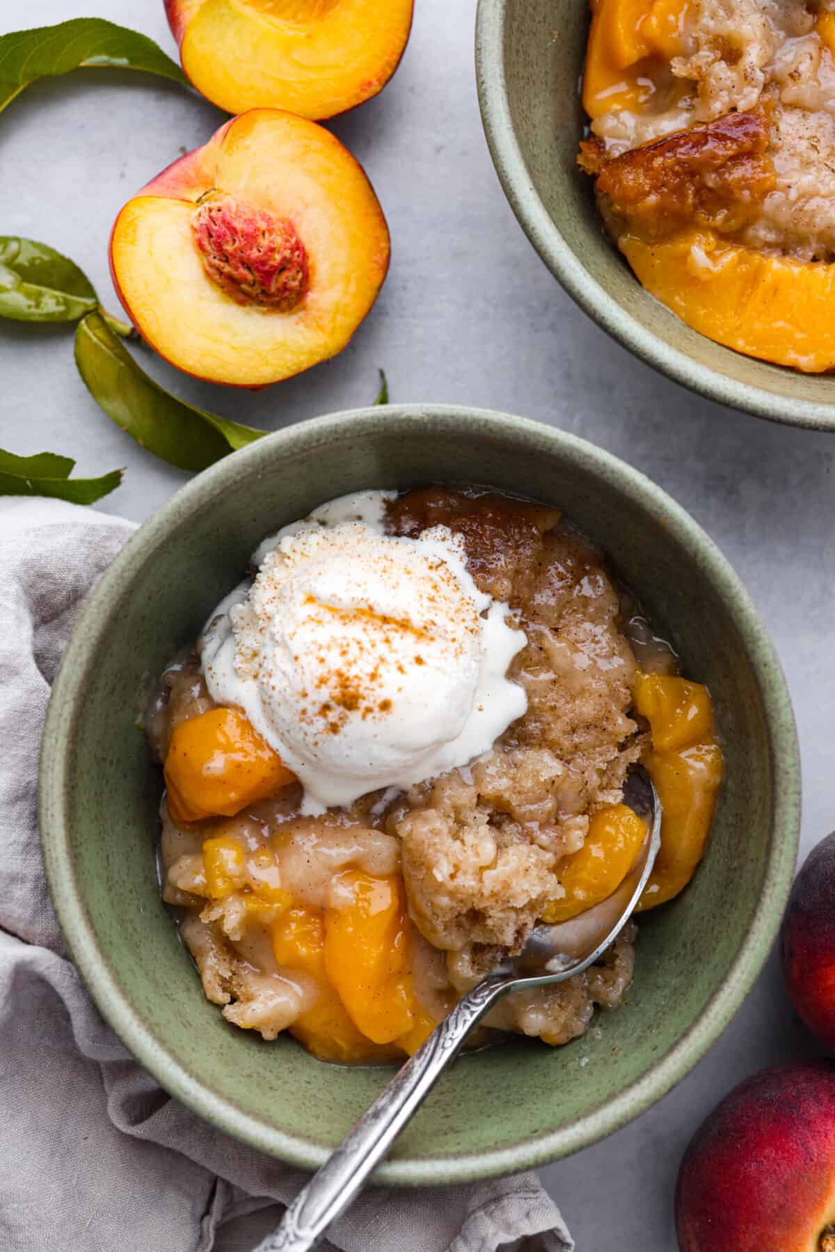 A bowl of peach cobbler with a scoop of vanilla ice cream on top. 
