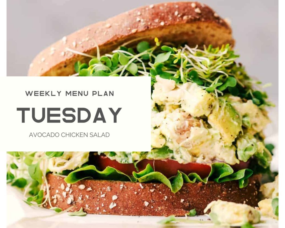 Avocado chicken salad in a sandwich with the weekly menu plan Tuesday over top. 