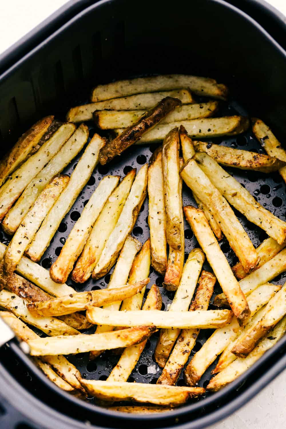 Crispy on the outside, tender on the inside air fryer french fries in the bottom of an air fryer basket.