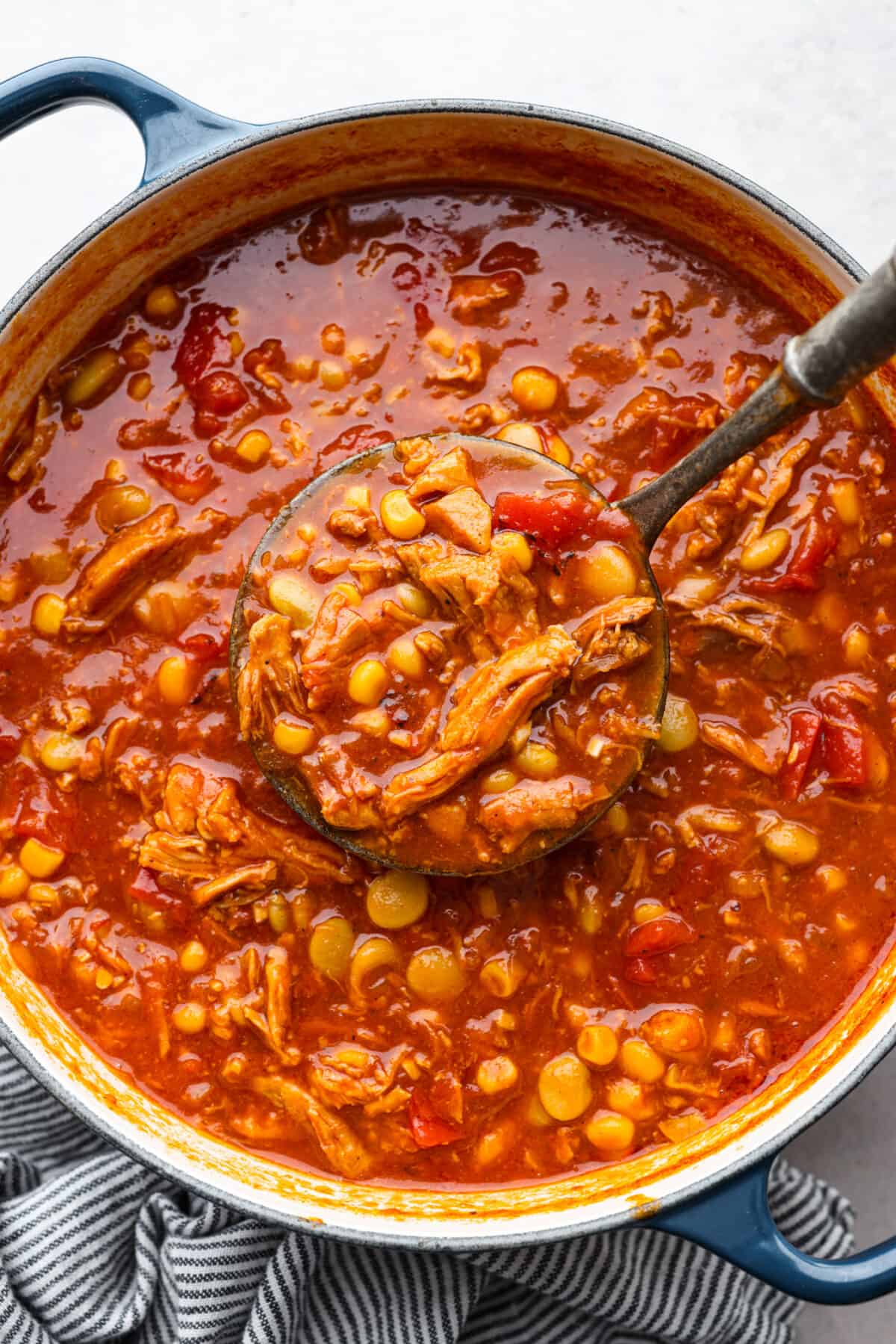 Cooked Brunswick stew in a large pot, being scooped up with a ladle.