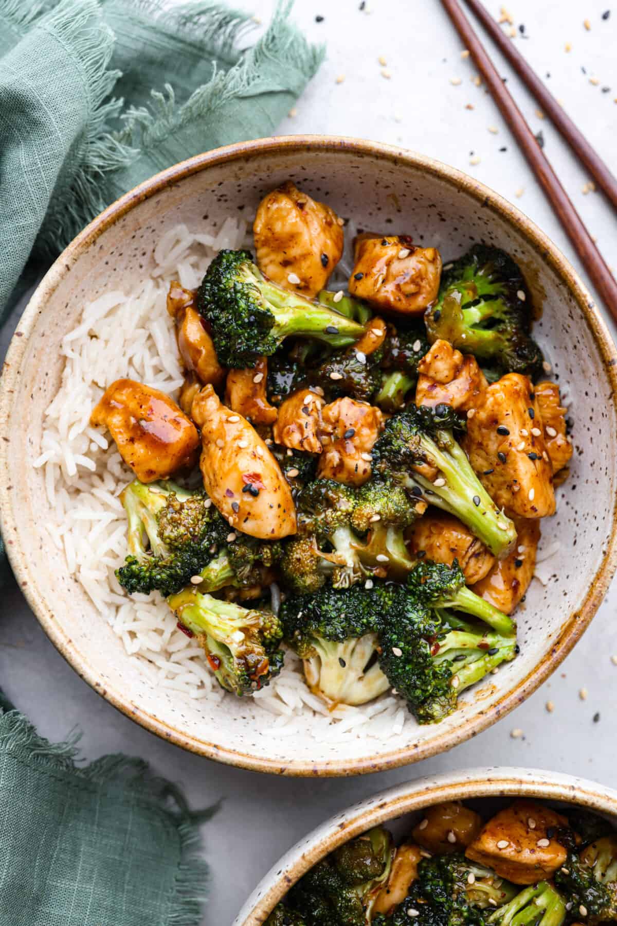Chinese chicken and broccoli served in a stoneware bowl with white rice.