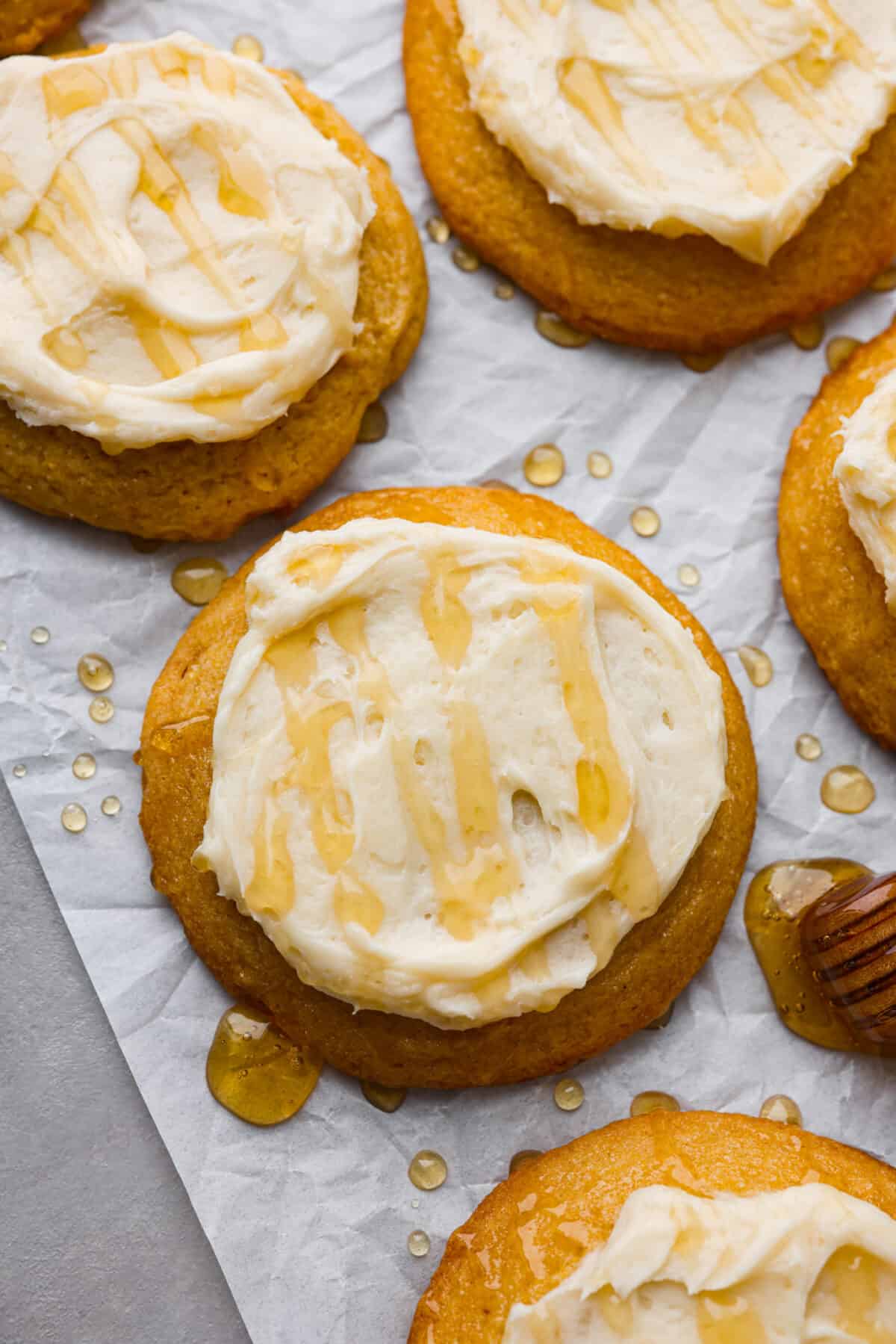 Close top view of cornbread cookies with frosting spread on top with a drizzle of honey.