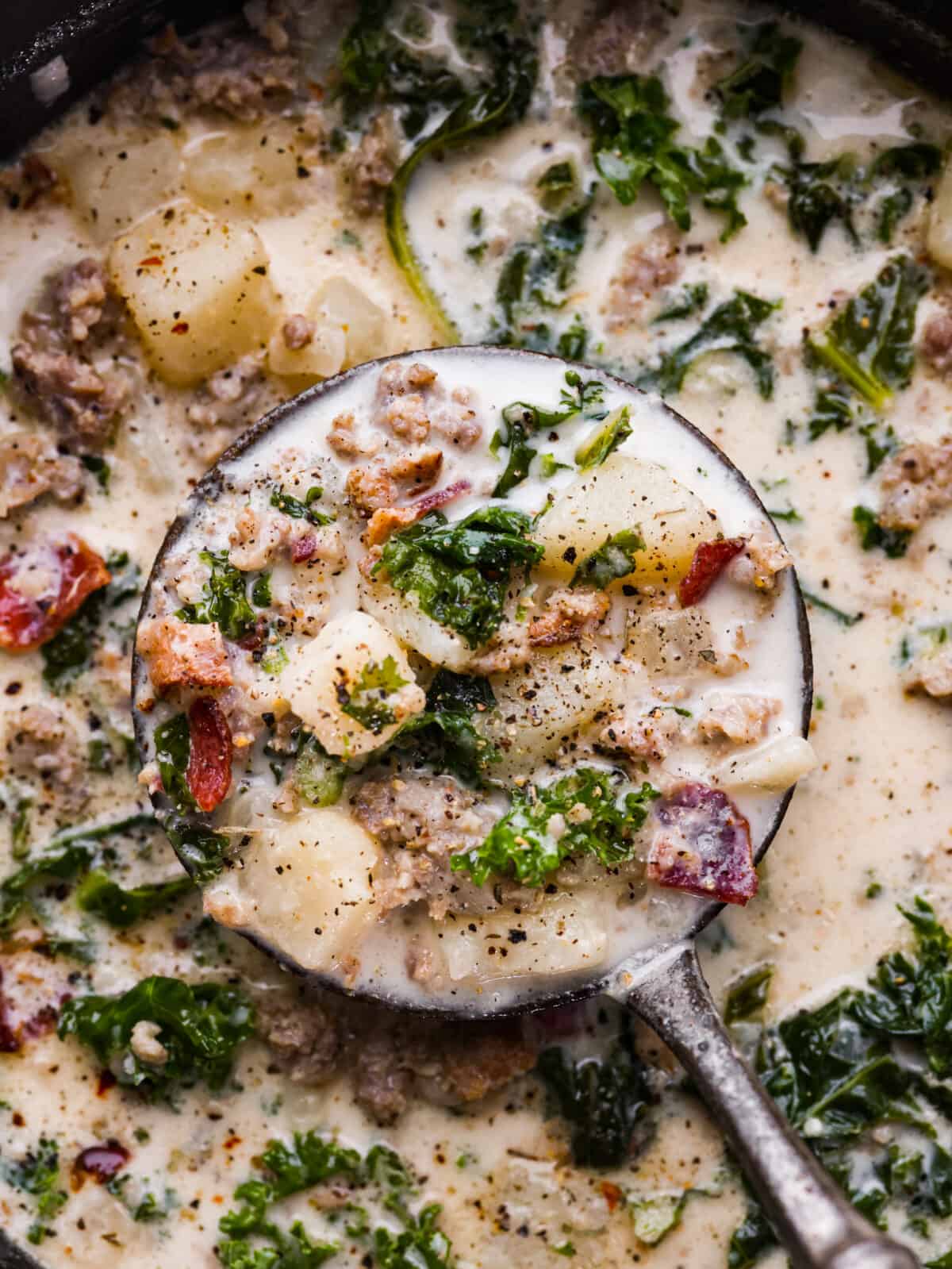 A close up of Zuppa Toscana in a ladel. 